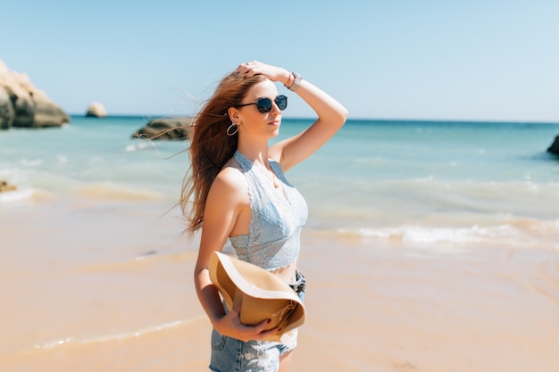 Jeune jolie femme au chapeau sur la plage à l'océan