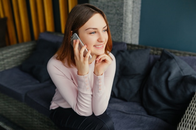 Jeune jolie femme avec bonne humeur parlant sur smartphone mobile avec son amie