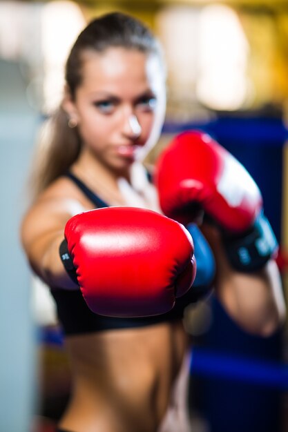 Jeune jolie femme de boxeur debout sur l'anneau et faire de l'exercice avec sac de boxe