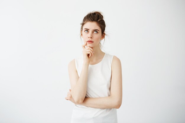 Jeune jolie femme avec chignon pensant rêver en regardant de côté.