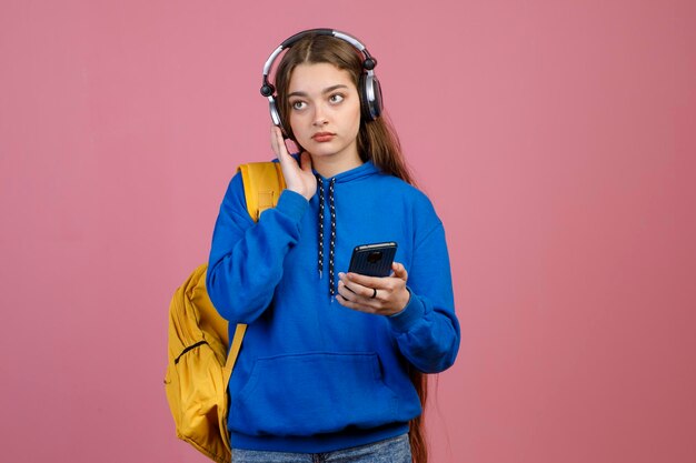 Jeune jolie femme debout tenant à l'aide d'un smartphone