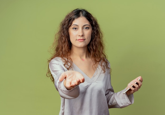 Photo gratuite jeune jolie femme employé de bureau tenant le téléphone et tenant la main isolée sur le mur vert olive