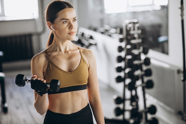 Jeune jolie femme exerçant avec des haltères au gymnase