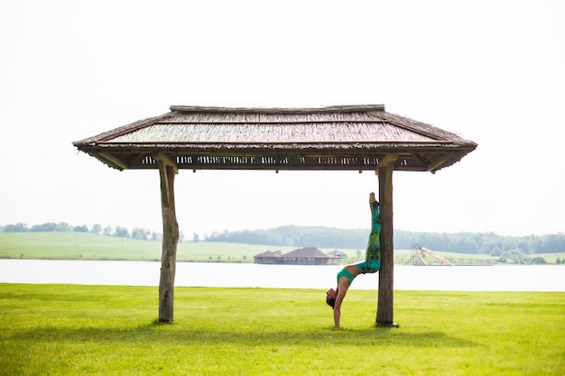 Jeune jolie femme faisant du yoga dans le parc du matin près du lac
