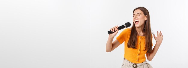 Jeune jolie femme heureuse et motivée chantant une chanson avec un microphone présentant un événement ou ayant