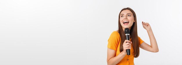 Jeune jolie femme heureuse et motivée chantant une chanson avec un microphone présentant un événement ou ayant