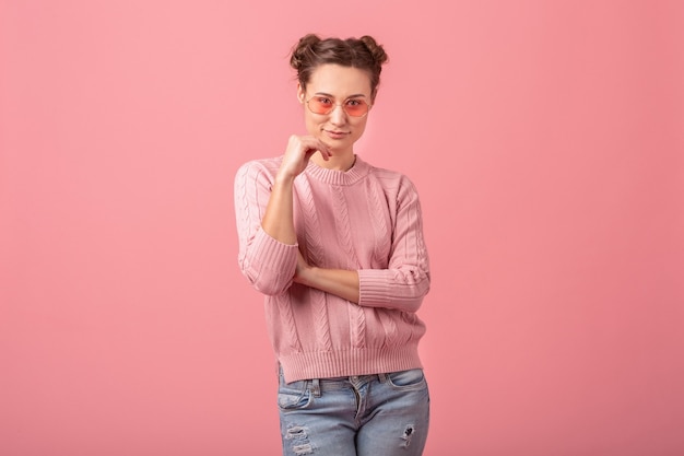 Photo gratuite jeune jolie femme avec joli sourire en pull rose et lunettes de soleil isolé sur fond rose studio, tendance de la mode printemps