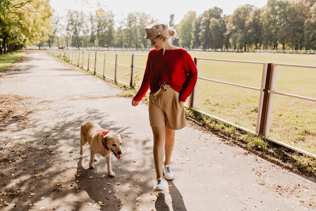 Jeune jolie femme jouant avec son chien dans le parc. Belle labrador blonde et blanche s'amusant ensemble.