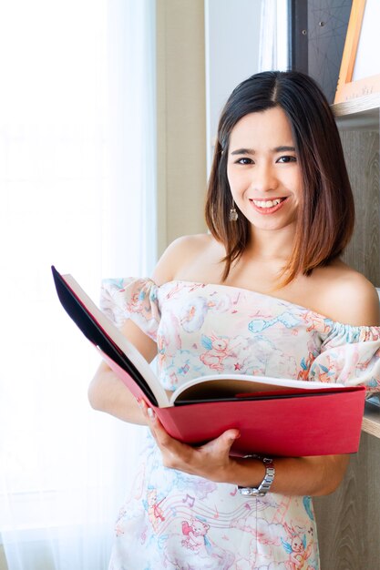 Jeune jolie femme lisant un livre à la maison