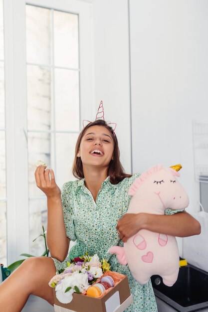 Jeune jolie femme mangeant un gâteau dans une cuisine moderne.