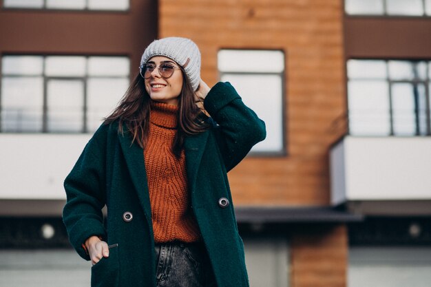 Jeune jolie femme en manteau chaud près de la maison