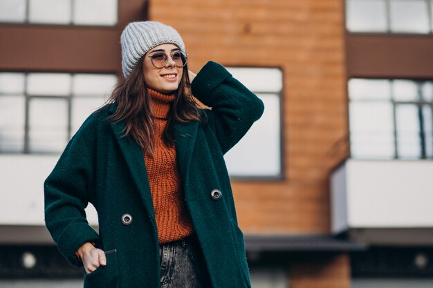 Jeune jolie femme en manteau chaud près de la maison