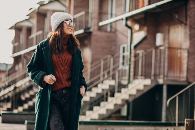 Jeune jolie femme en manteau chaud près de la maison