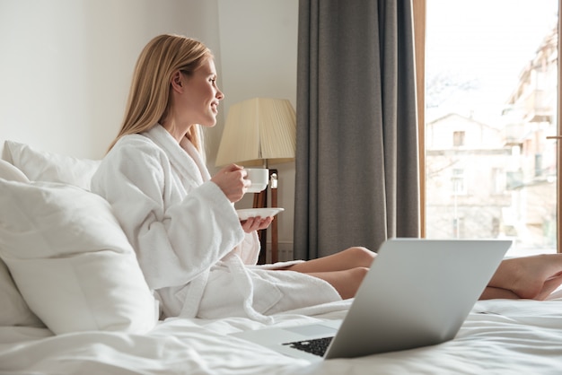 Jeune jolie femme en peignoir, boire du café