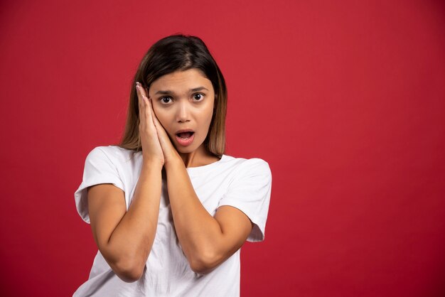 Jeune jolie femme posant sur un mur rouge.