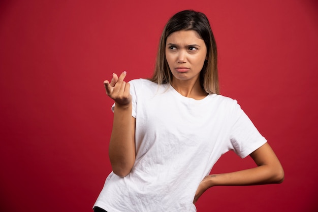 Jeune jolie femme posant sur un mur rouge.