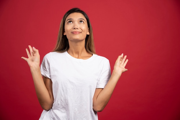 Jeune jolie femme posant sur un mur rouge.