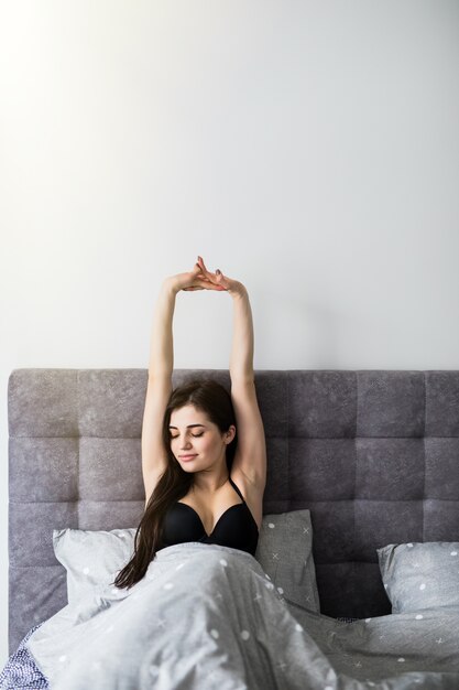 Jeune jolie femme qui s'étend dans le lit. Concept du matin