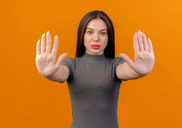 Photo gratuite jeune jolie femme regardant la caméra et arrêt de gestes isolé sur fond orange