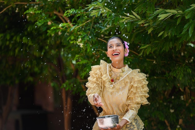 Jeune jolie femme s'habille de beaux costumes thaïlandais éclaboussant de l'eau dans les temples et préservant la bonne culture du peuple thaïlandais pendant le festival de Songkran Journée de la famille du Nouvel An thaïlandais en avril