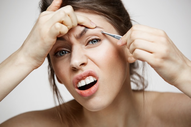 Jeune jolie femme avec des sourcils tweeze peau propre parfaite faisant la grimace. Beauté et spa.