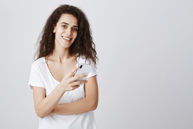 Jeune jolie femme souriante, à l'aide de smartphone