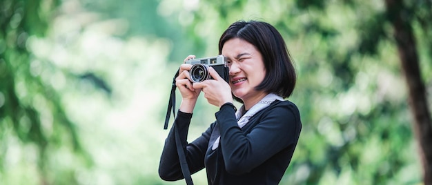 Jeune jolie femme utilise un appareil photo numérique en prenant une photo de la belle nature en camping dans la forêt avec un espace de copie de bonheur