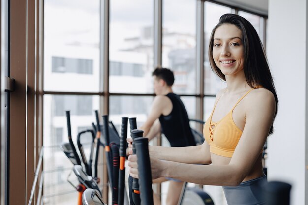 Jeune jolie fille au gymnase sur un vélo d'exercice, fitness et yoga