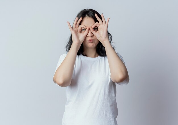 Jeune jolie fille caucasienne faisant regarder le geste à la caméra à l'aide des mains comme des jumelles et faire le geste de baiser isolé sur fond blanc avec espace de copie