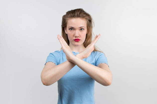 Photo gratuite jeune jolie fille en chemise bleue et beaux cheveux montrant le panneau d'arrêt