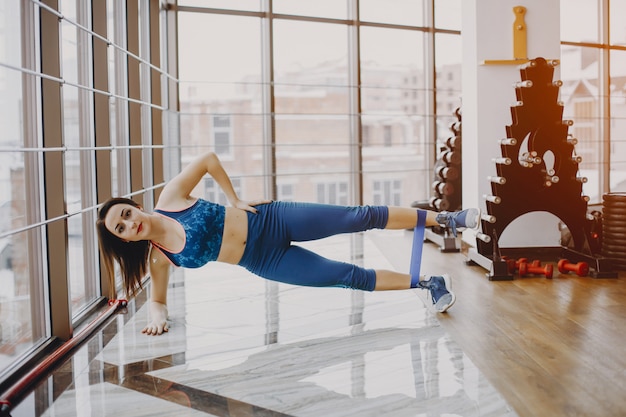 Jeune et jolie fille dans un costume de sport bleu est engagée dans les sports dans la salle de gym