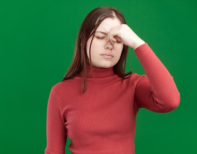 Jeune jolie fille fatiguée tenant le nez avec les yeux fermés