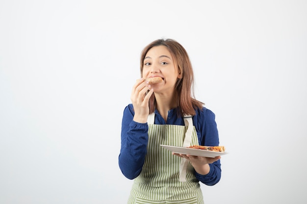 jeune jolie fille mangeant de la pizza sur blanc.