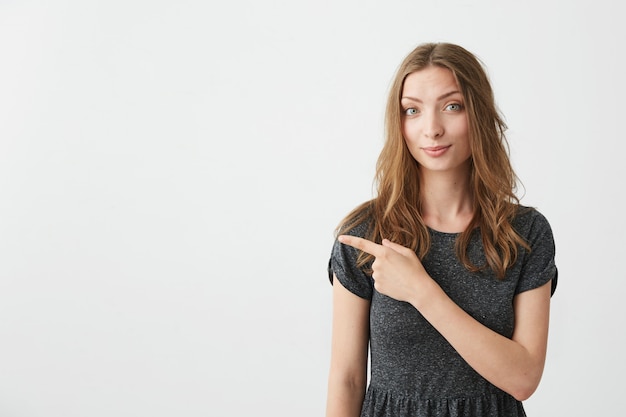 Jeune jolie fille positive souriant doigt pointé sur le côté.