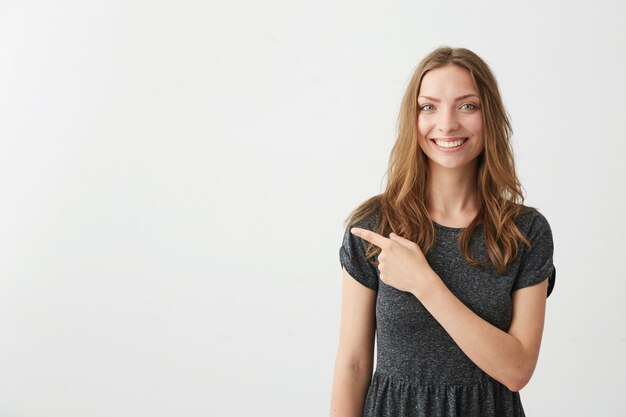 Jeune jolie fille positive souriant doigt pointé sur le côté.