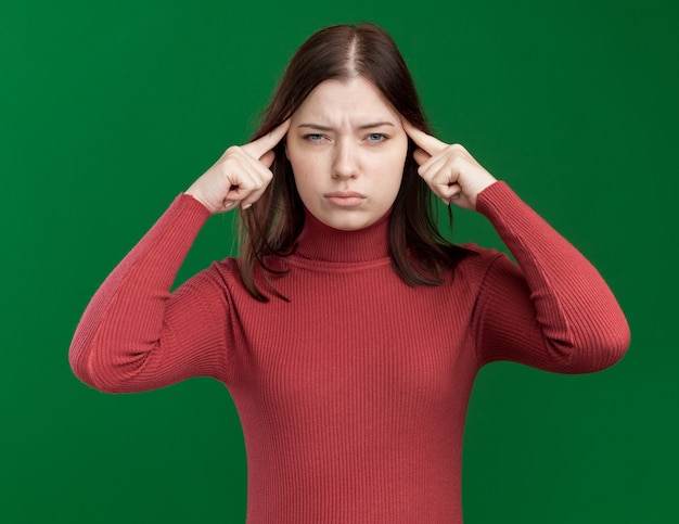 Jeune jolie fille réfléchie faisant un geste de réflexion isolé sur un mur vert