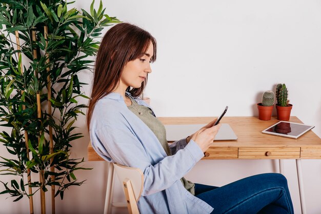 Jeune jolie fille avec téléphone à table