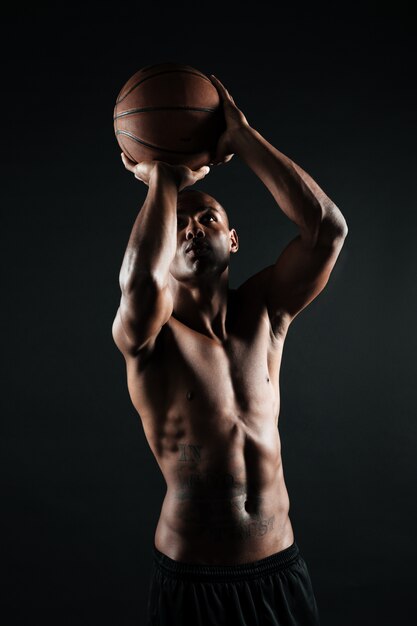 Jeune joueur de basket-ball afro-américain se prépare à lancer la balle dans le panier