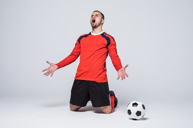 Jeune joueur de football heureux et excité en maillot rouge célébrant le but de marquer