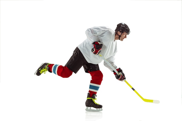 Jeune joueur de hockey masculin avec le bâton sur le court de glace et fond blanc.