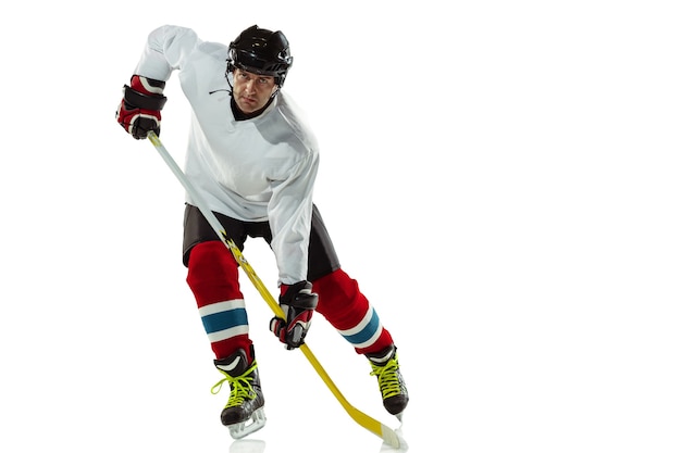 Jeune joueur de hockey masculin avec le bâton sur le court de glace et fond blanc.