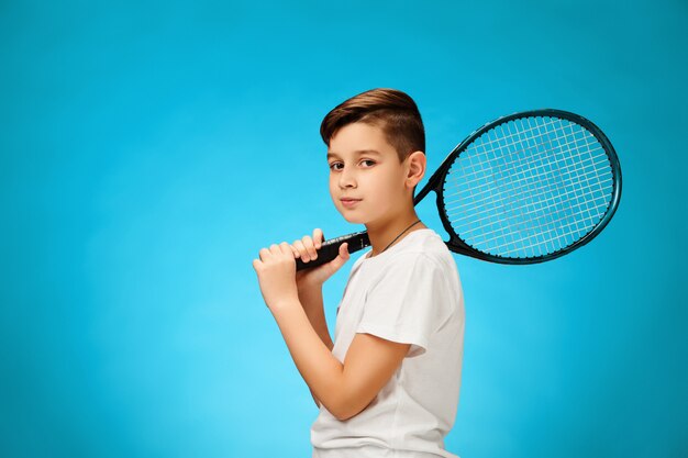 Jeune joueuse de tennis sur mur bleu.