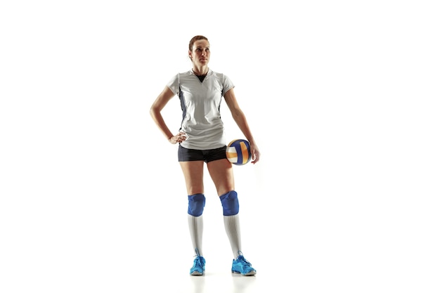 Jeune joueuse de volley-ball isolée sur un mur blanc. Femme en équipement de sport et chaussures ou baskets s'entraînant et pratiquant. Concept de sport, mode de vie sain, mouvement et mouvement.