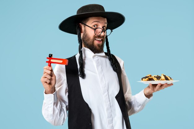 Le jeune juif orthodoxe avec des biscuits hamantaschen pour le festival Pourim. Vacances, célébration, judaïsme, pâtisserie, tradition, cookie, concept de religion
