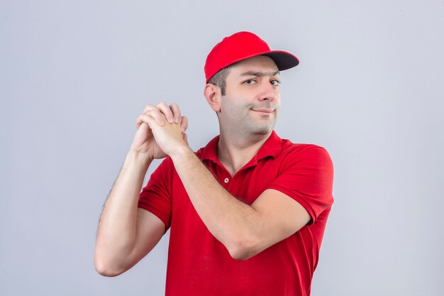 Jeune livreur en polo rouge et casquette debout avec un geste de travail d'équipe sur fond blanc isolé