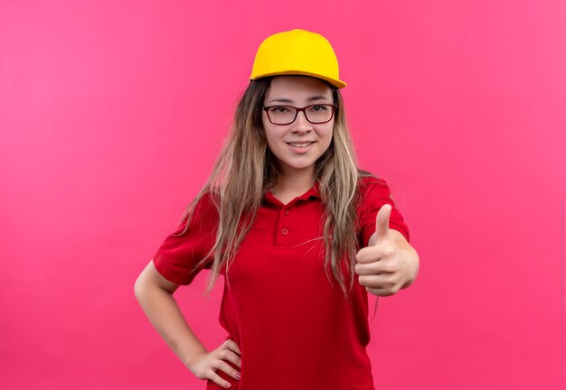 Jeune livreuse en polo rouge et casquette jaune souriant montrant les pouces vers le haut