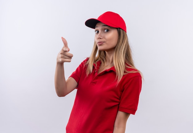 Jeune livreuse portant l'uniforme rouge et une casquette montrant le geste du pistolet isolé sur un mur blanc