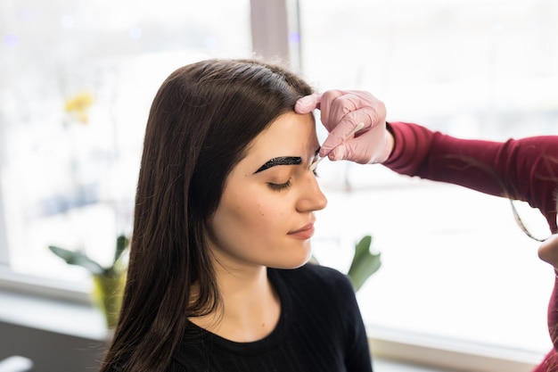 Jeune maître des sourcils faisant de son mieux dans la procédure de maquillage