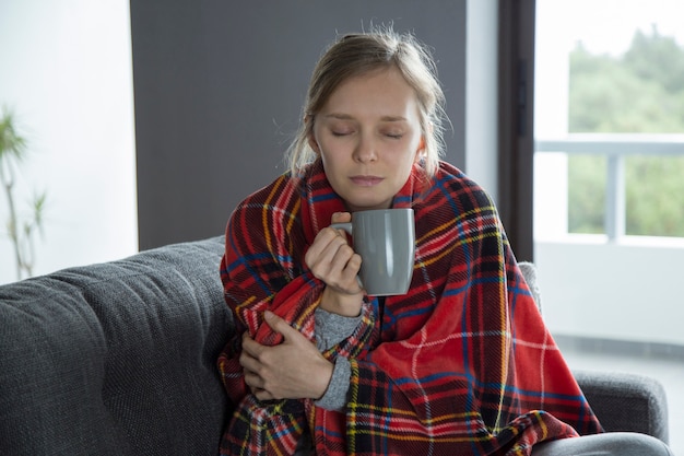 Photo gratuite jeune malade aux yeux fermés tenant une tasse à la main, fébrile