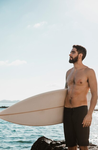 Jeune mâle avec planche de surf près de la mer